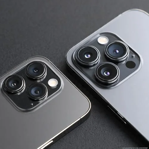 Side-by-side top-down comparison of the iPhone 16 Pro and iPhone 16 Pro Max, highlighting the physical difference in size between their nearly identical triple-lens camera systems.
