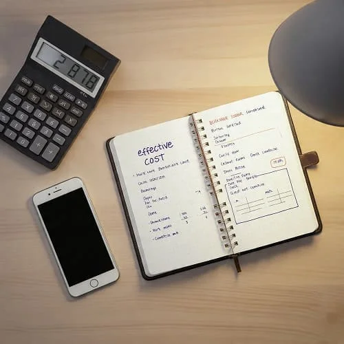 Phone beside calculator and notes calculating preorder effective cost