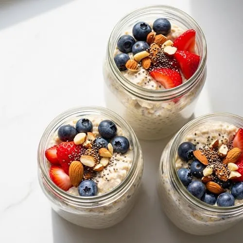 High protein overnight oats in jars with berries, nuts, and chia seeds